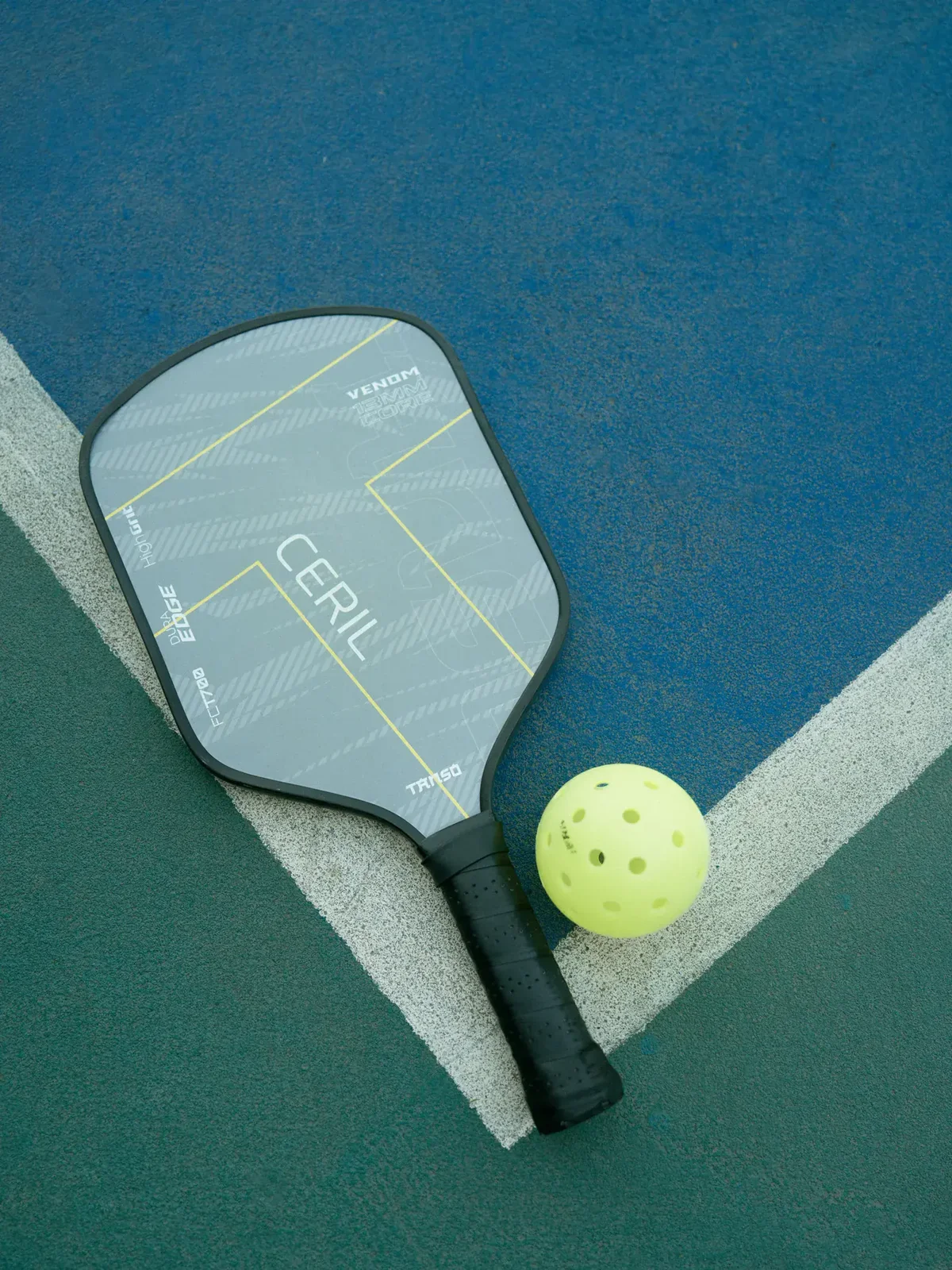 A pickleball paddle and ball resting on the court’s kitchen line